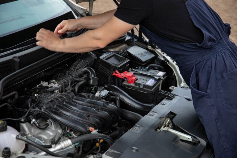 Mechanik serwisujący silnik samochodu na zewnątrz w dzień